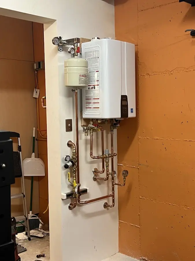 Plumbing technician inspecting water heater connections in Landen